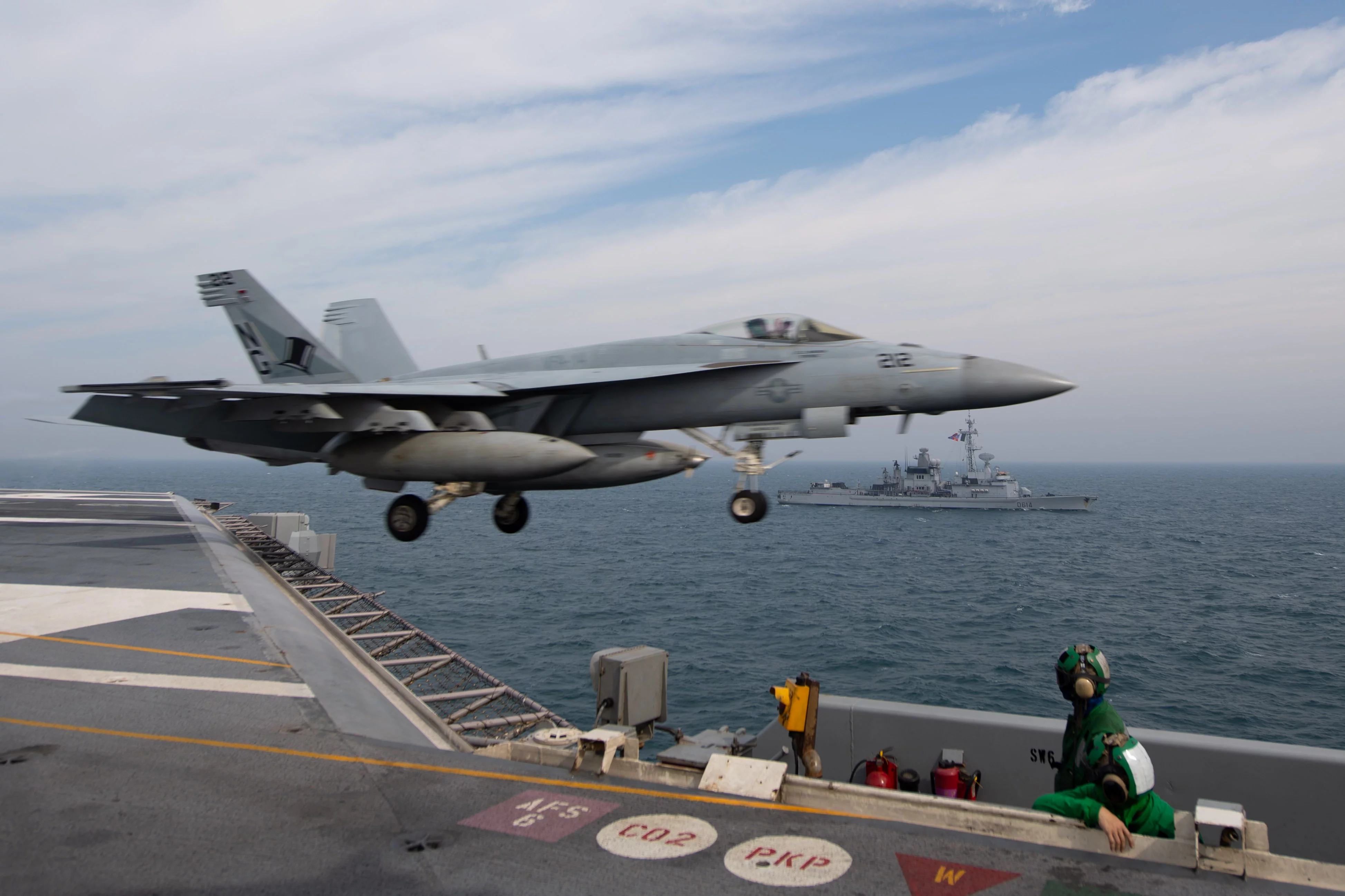 Un chasseur F-18 décole du porte-avions USS John C. Stennis devant la frégate Cassard