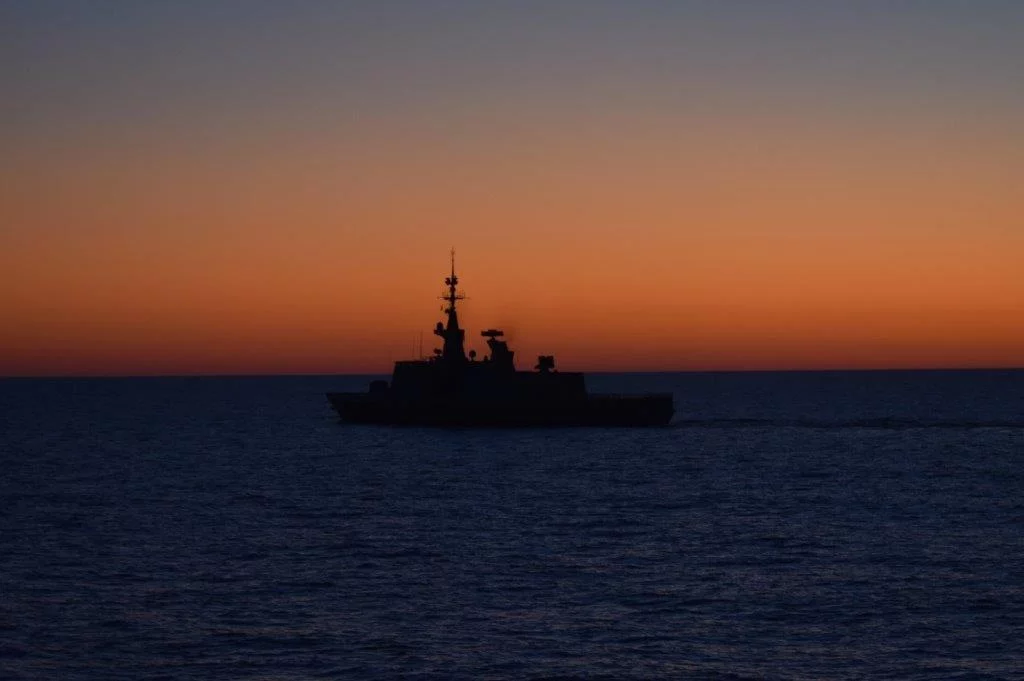 La frégate Aconit à contre-jour sur le soleil couchant