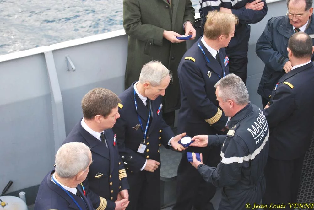 Le commandant actuel remet à un de ses prédécesseurs une médaille et une casquette