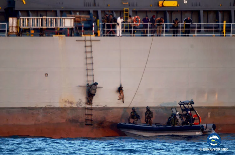 L'équipe de visite et le chien montent à bord d'un navire