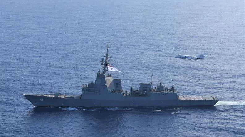 Un avion de surveillance maritime Falcon F200 Gardian survole la frégate australienne Brisbane