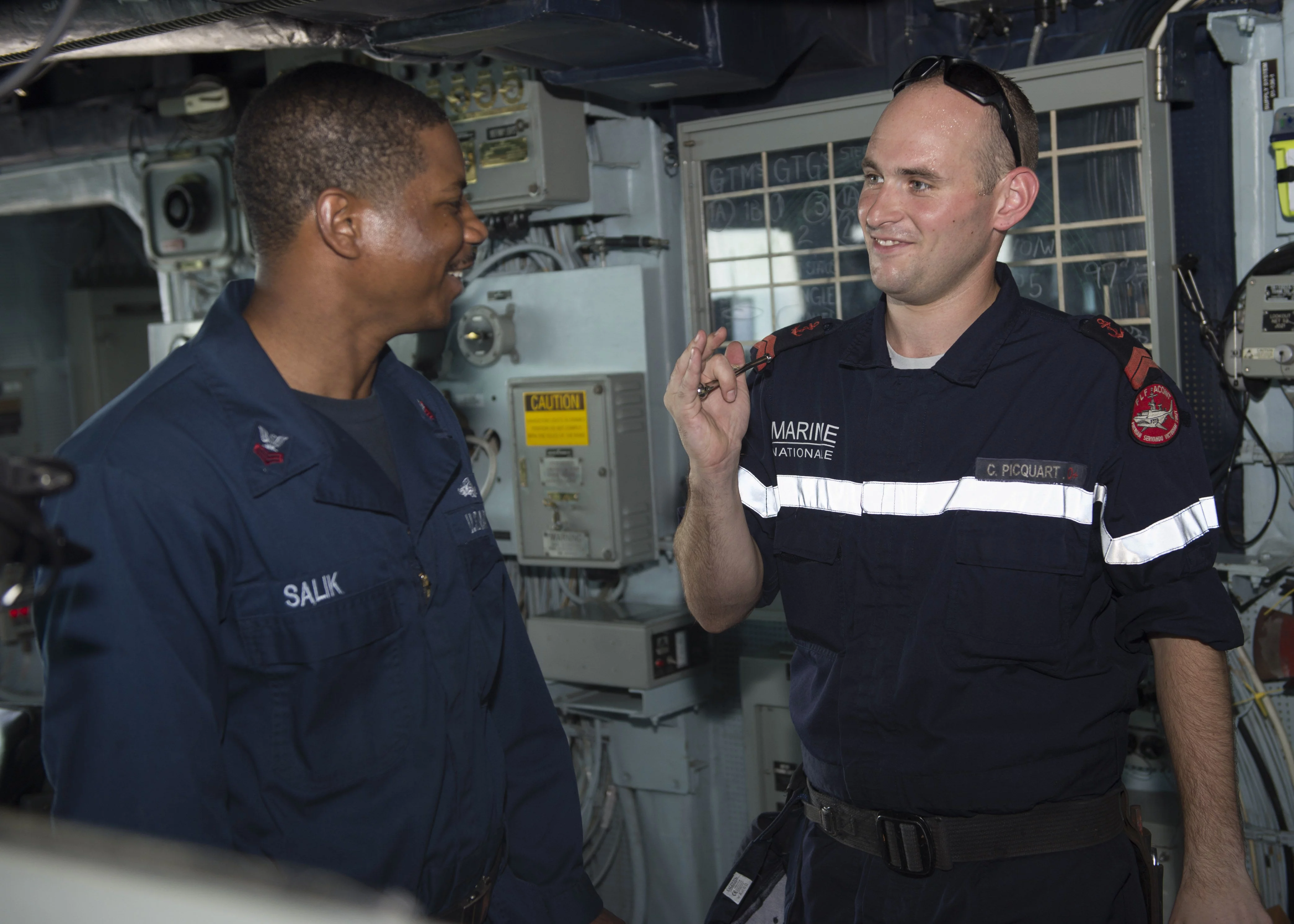 Le manoeuvrier de 1ère classe Antoine Salik, du destroyer USS Bulkeley, partage des techniques de sifflet avec le quartier-maître de 2è classe Clément Picquart, de la frégate Aconit