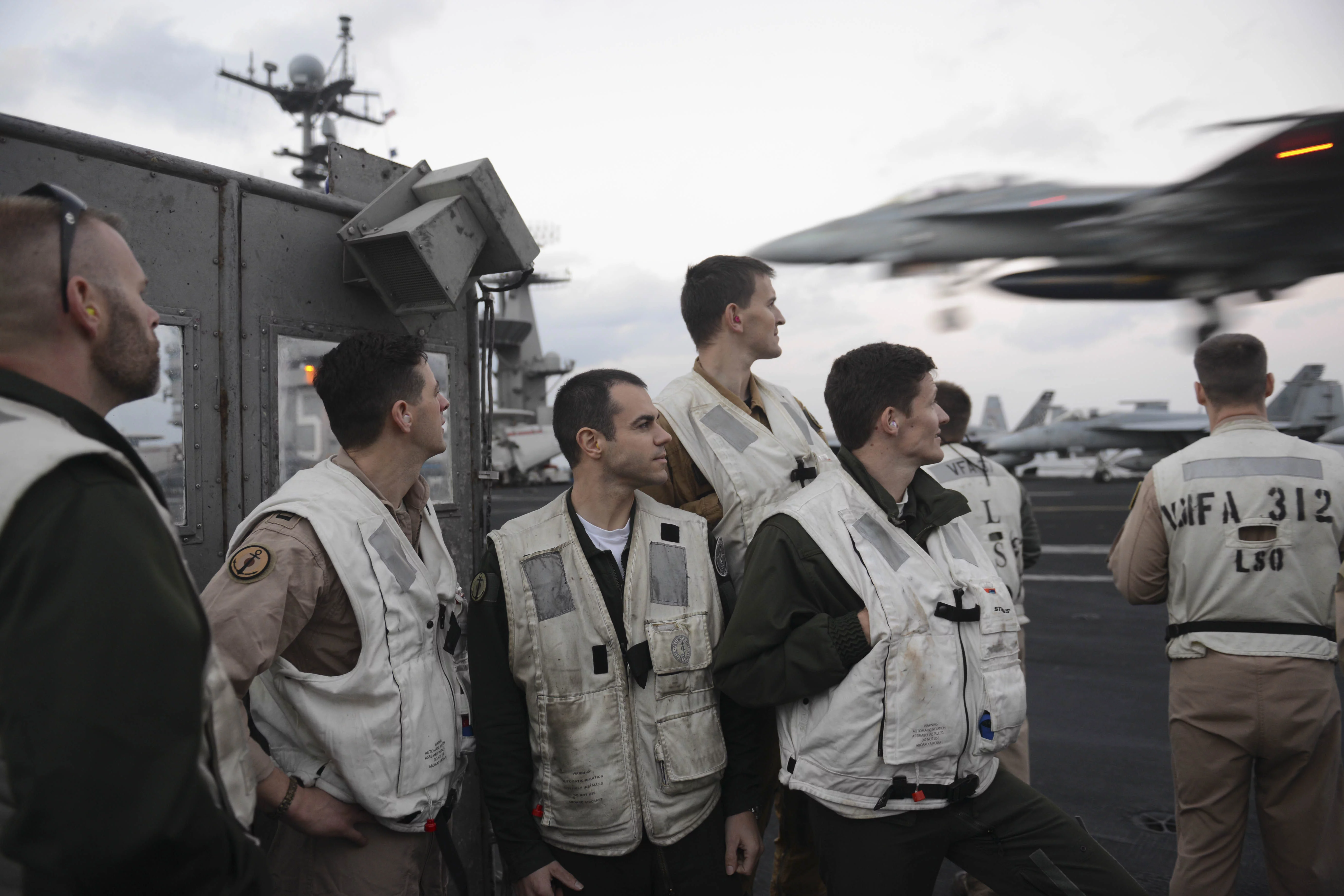 Des pilotes du Charles de French assistent à l'appontage d'avions depuis la plateforme de signalisation du porte-avions USS Harry S. Truman