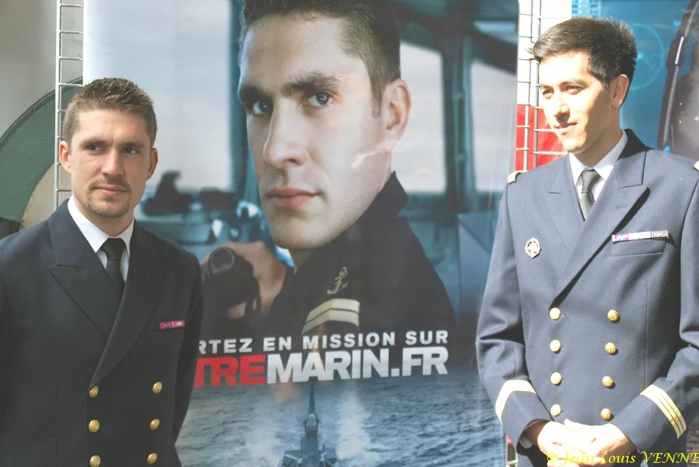 Les 2 marins devant les affiches de la campagne