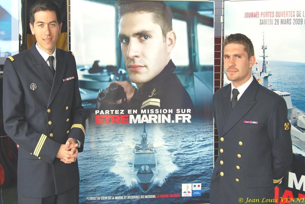 Les 2 marins devant les affiches de la campagne
